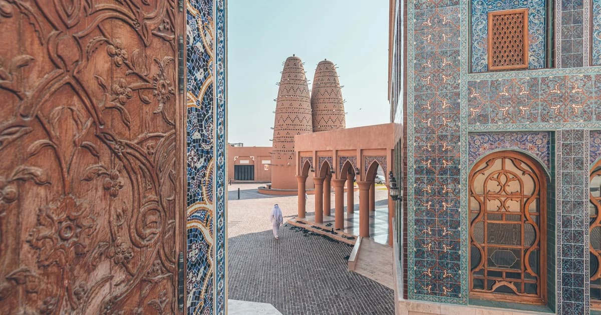 Blue tiled facade of Katara Mosque framing the pigeon towers at Katara Cultural Village in Doha