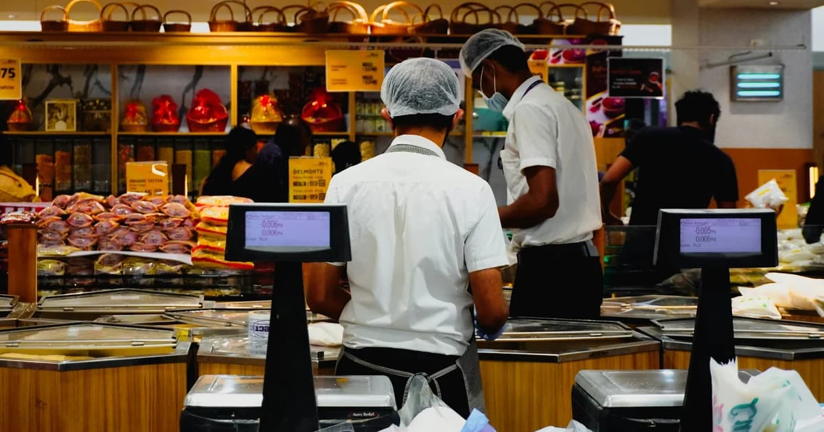 Hypermarket counter staff in white uniforms and hairnets working a shift
