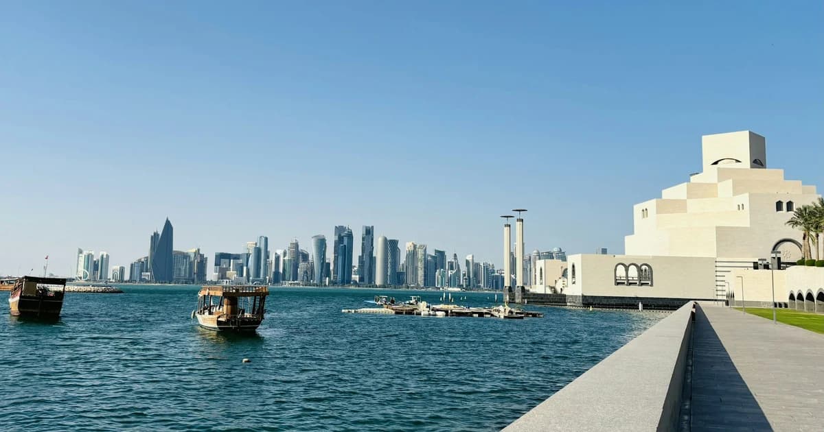 Doha skyline on a hot, cloudless day seen from the Museum of Islamic Art waterfront with dhows on the bay