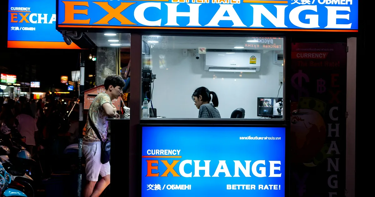 A customer at a currency exchange counter, illustrating the in-branch remittance process described in this guide. Photo not taken in Qatar.