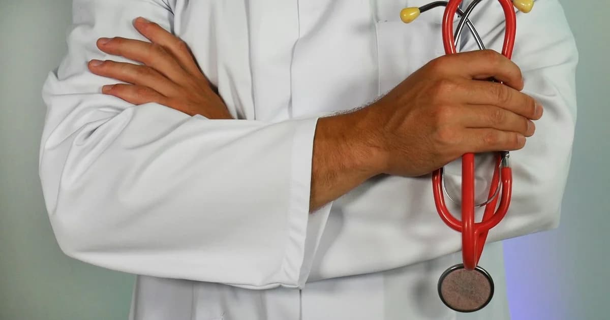 A doctor in a white coat holding a stethoscope, representing a Qatar medical fitness test