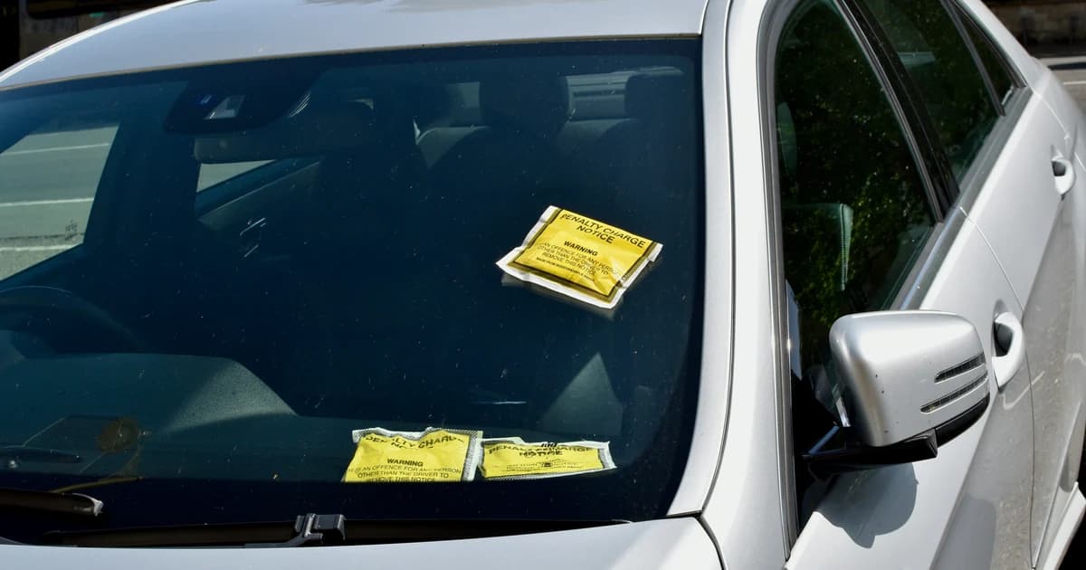 Traffic penalty charge notices placed under the windshield wiper of a parked car