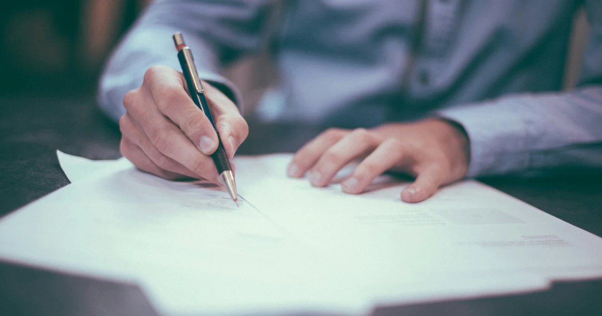 Close-up of a hand signing a government application form