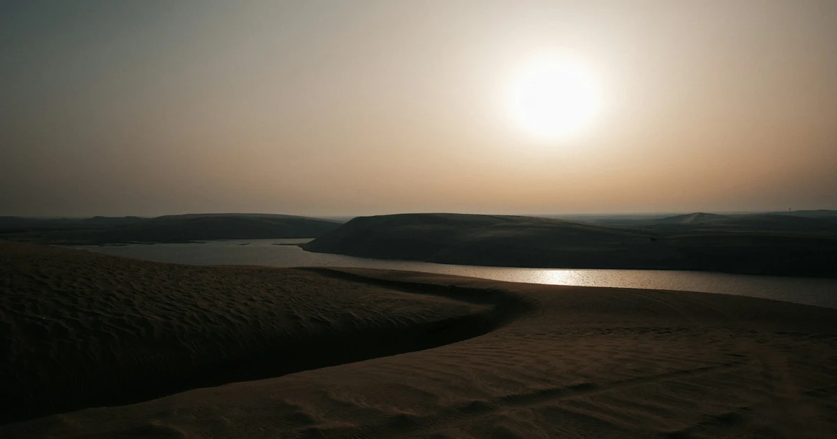 Sunset over the Inland Sea at Khor Al Adaid, with sand dunes on both sides of the lagoon