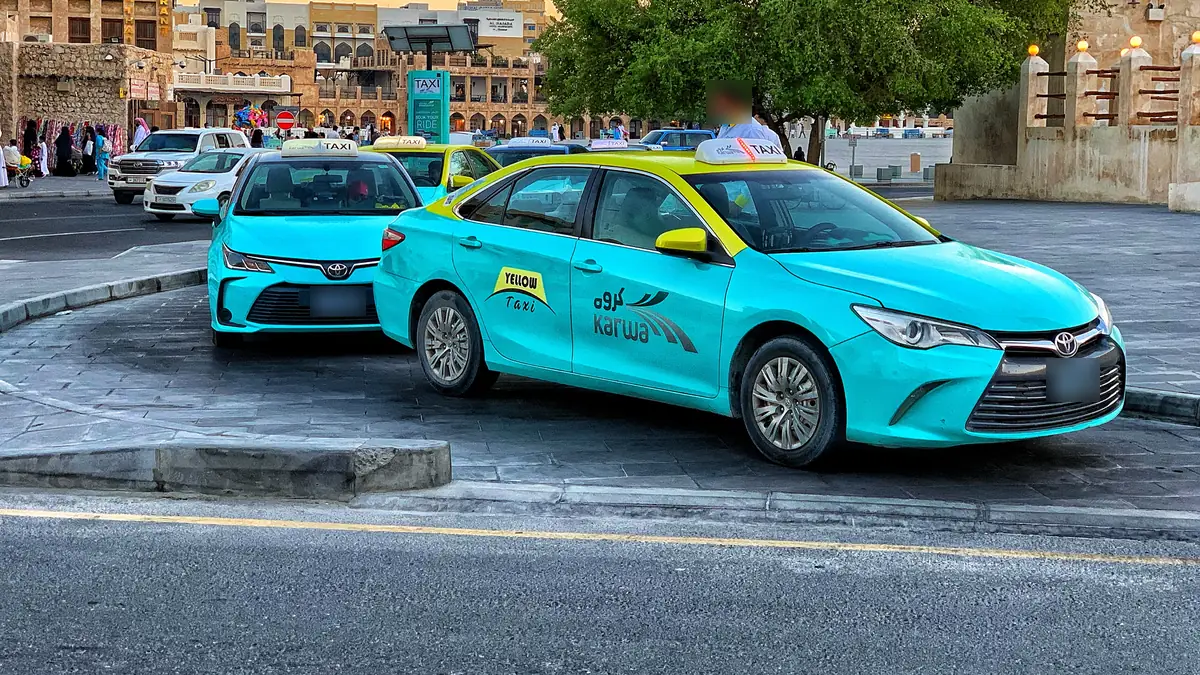 Turquoise Karwa taxis with yellow roofs waiting at a taxi stand near Souq Waqif in Doha