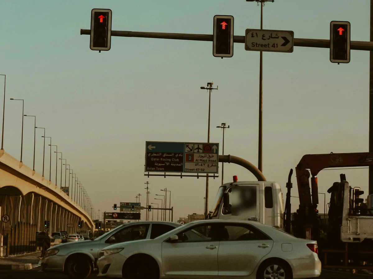 Cars and a crane truck stopped at red traffic lights beneath a Street 41 sign and a bridge in Qatar