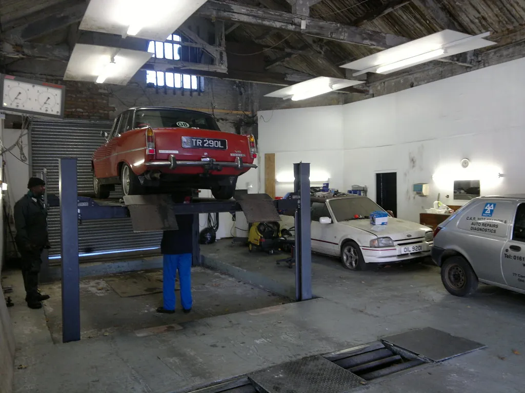 Car raised on a lift in a vehicle inspection lane while an inspector checks the underside