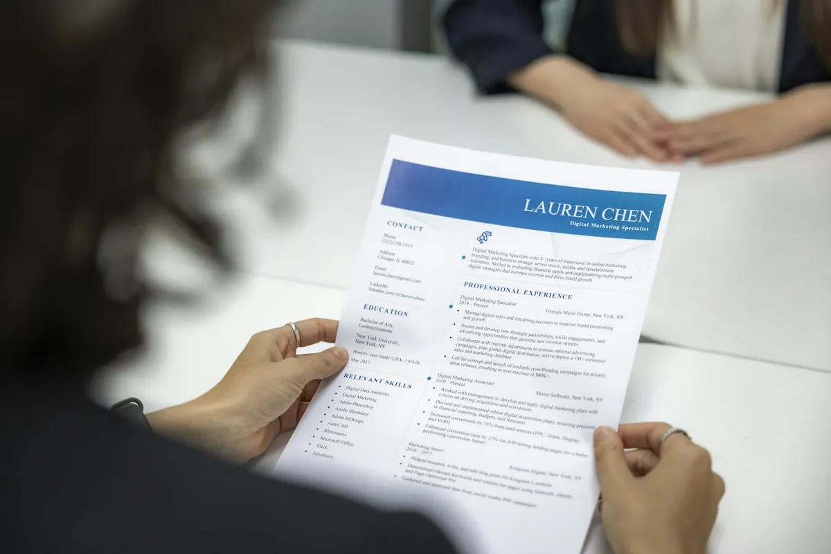 A person holding a printed CV across a table during an interview