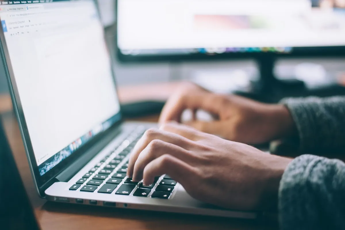 Hands typing on a laptop keyboard at a desk
