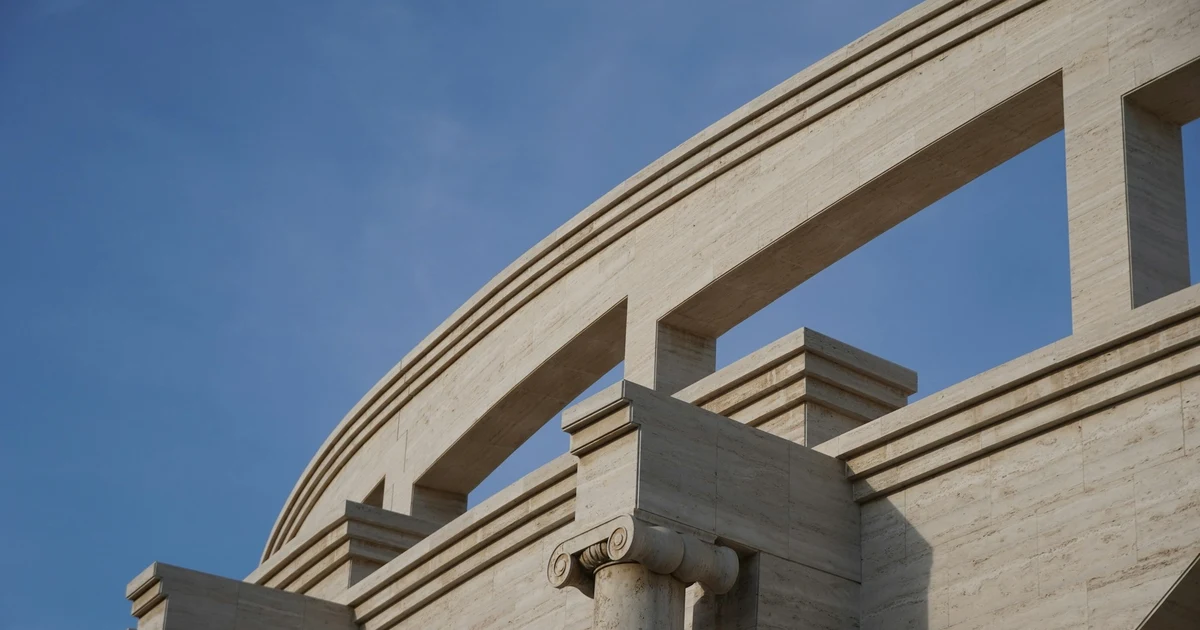 Curved stone arches and an Ionic column of the Katara Amphitheatre against a blue sky in Doha