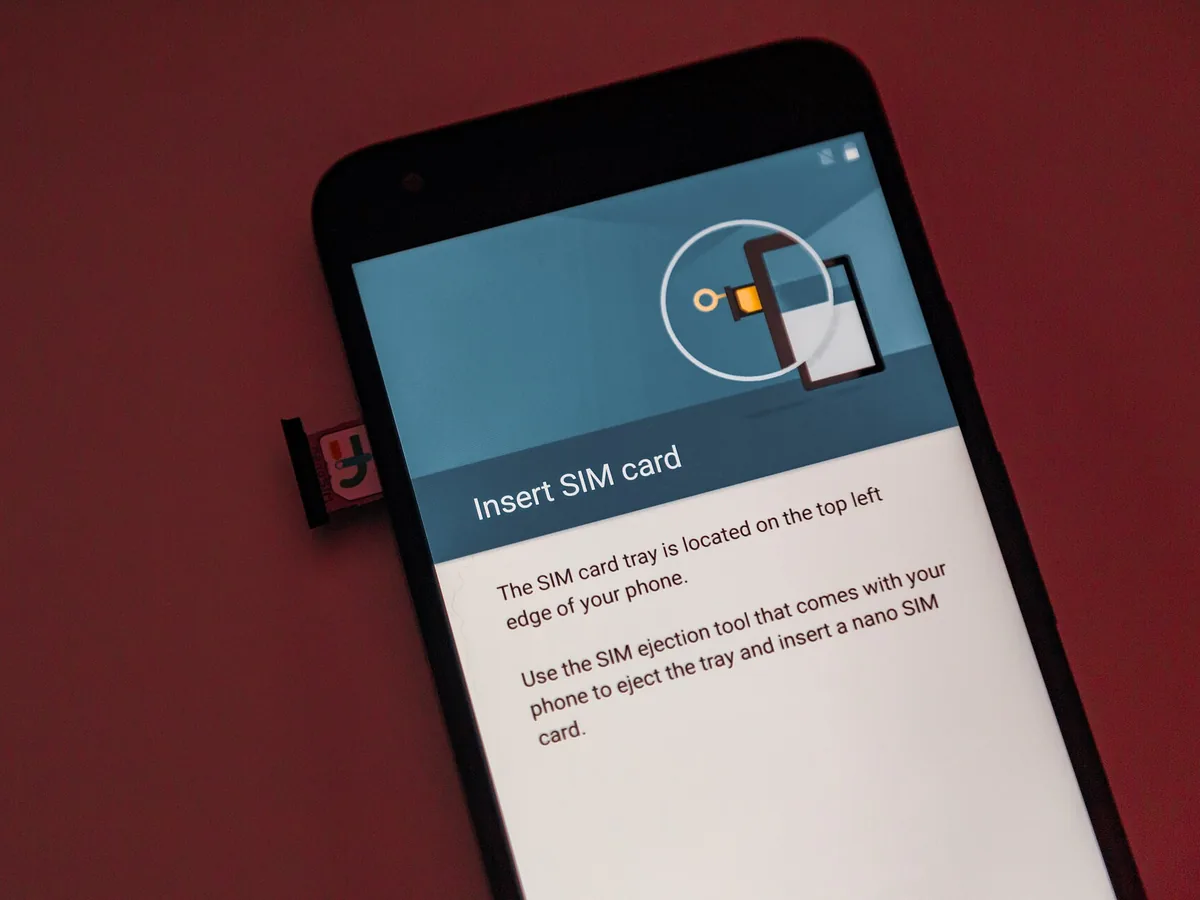 Smartphone setup screen asking the user to insert a SIM card, with the SIM tray ejected beside the phone