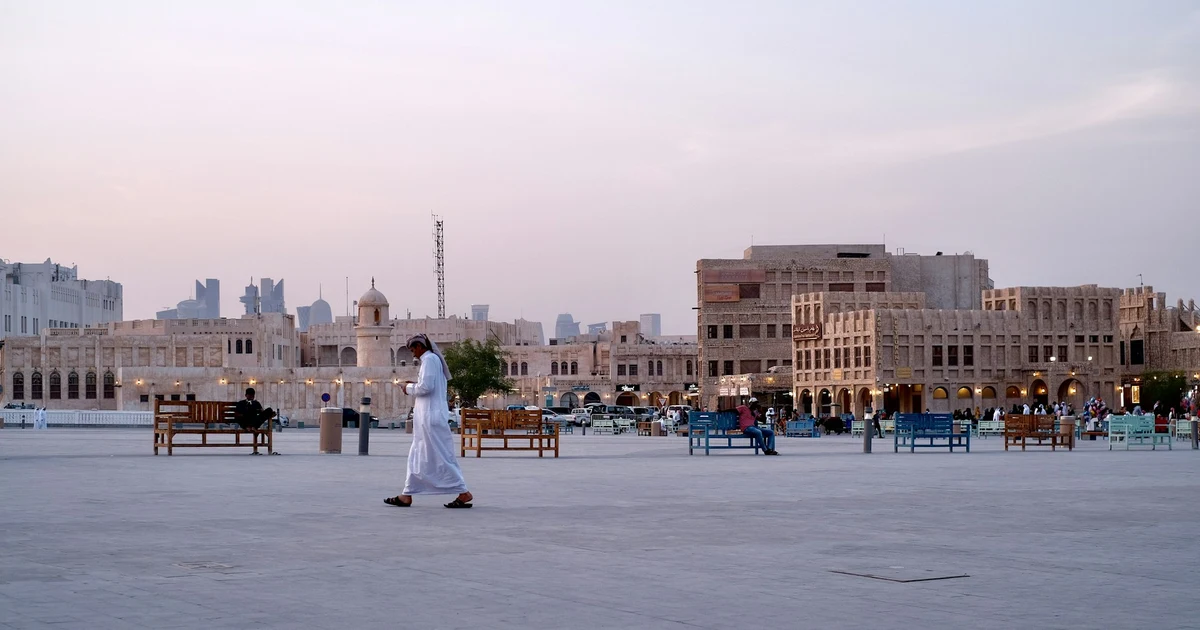 The main square at Souq Waqif at dusk, with the souq buildings and the Doha skyline behind