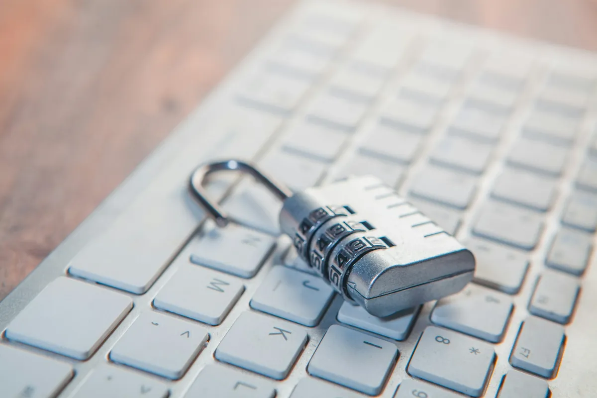 A combination padlock resting on a laptop keyboard, illustrating a locked or reset password