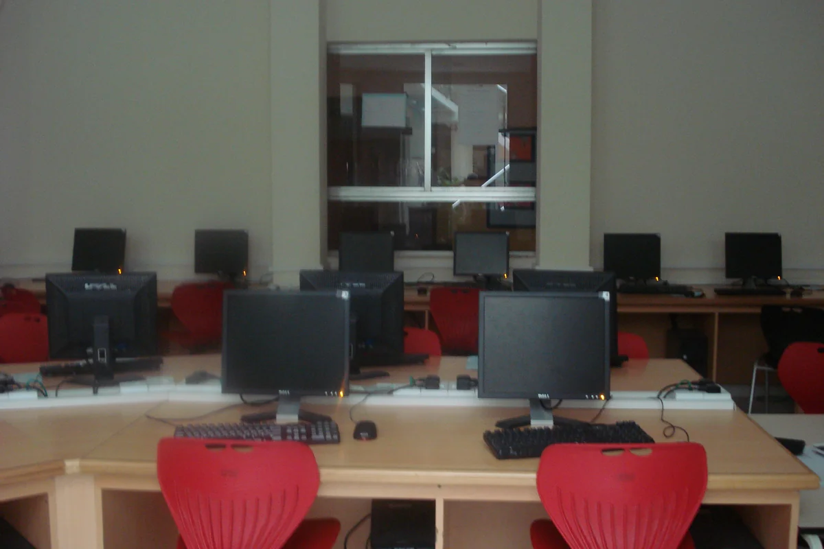 School computer lab with rows of desktop monitors and red chairs at a school in Doha, Qatar